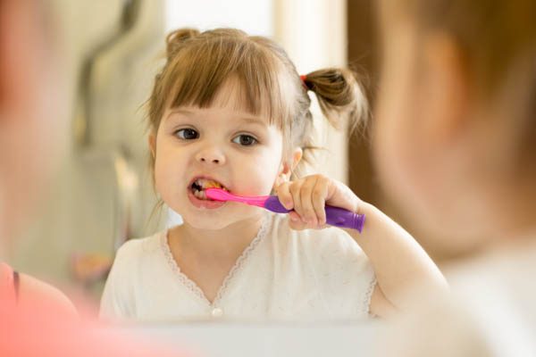 Cute,Child,Girl,Looking,At,Mirror,Using,Toothbrush,Cleaning,Teeth Cute child girl looking at mirror using toothbrush cleaning teeth in bathroom every morning and night.