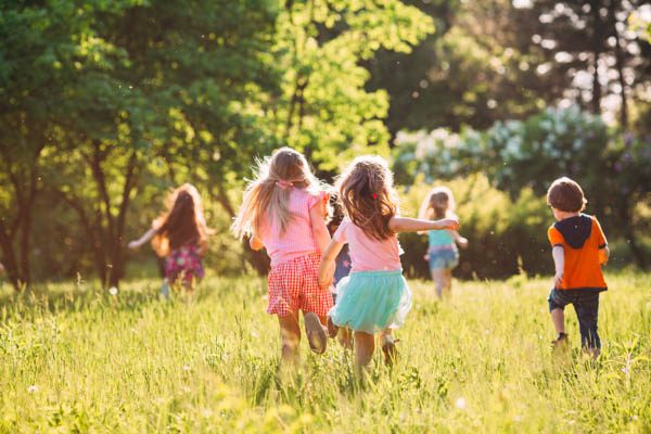 Large group of kids, friends boys and girls running in the park on sunny summer day in casual clothes